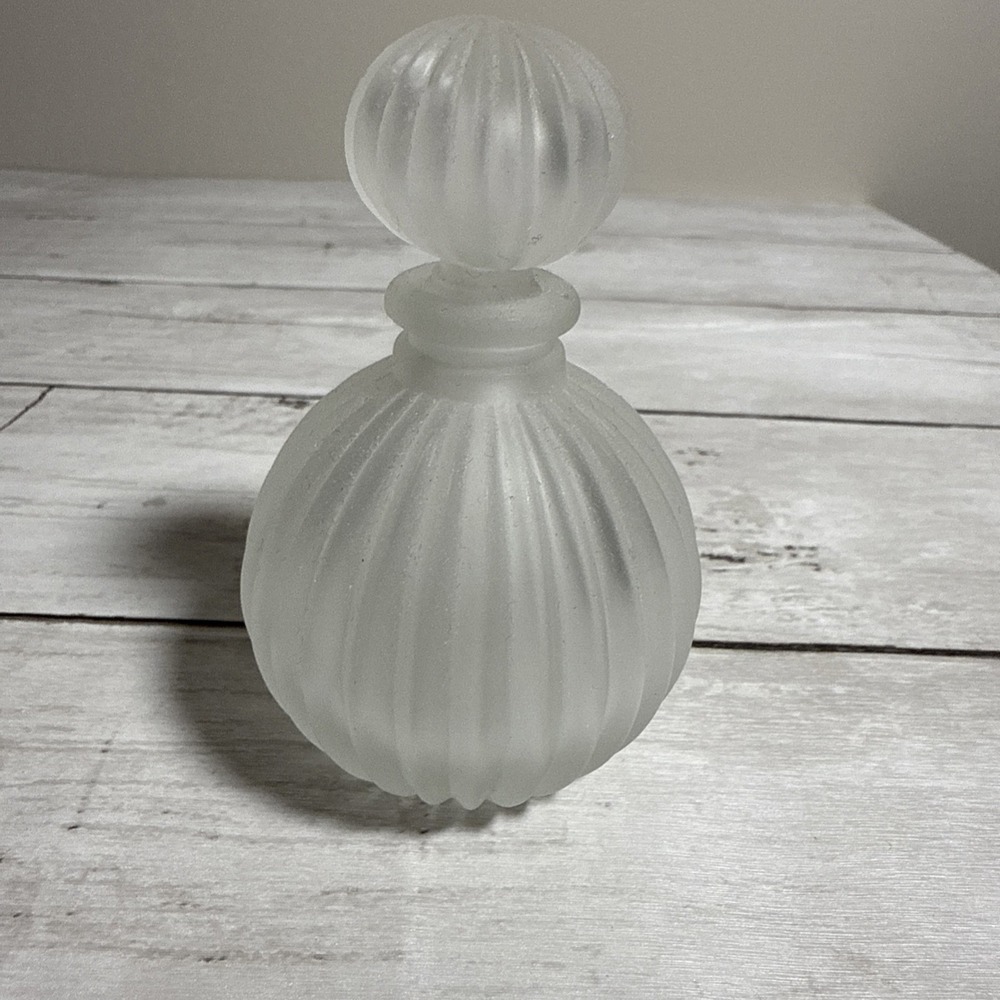 A vintage frosted glass ribbed perfume bottle with a stopper.